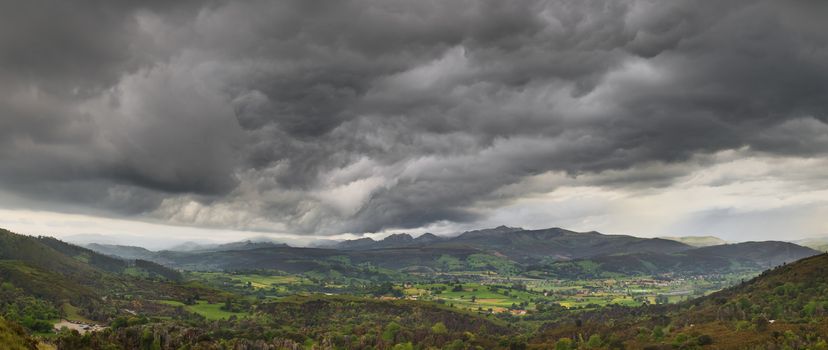 Dark stormy clouds over a green valley in Cantabria Spain