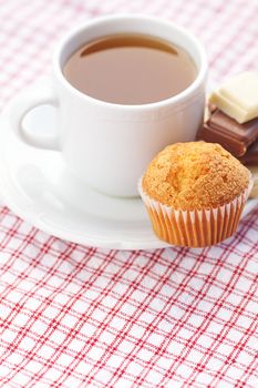 bar of chocolate,tea and muffin on plaid fabric