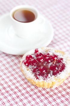 beautiful cake with berries  and tea on plaid fabric