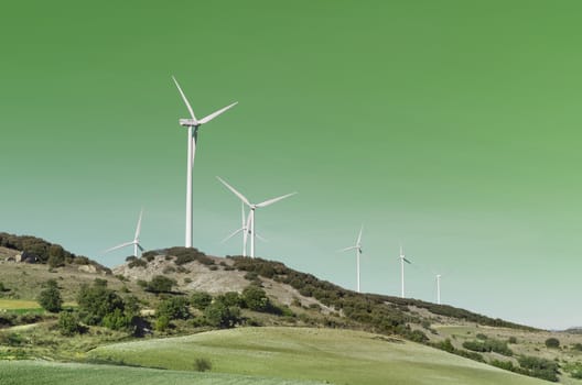  Wind turbines over Green background. Clean energy concept.