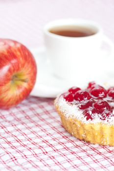 beautiful cake with berries,apple and tea on plaid fabric