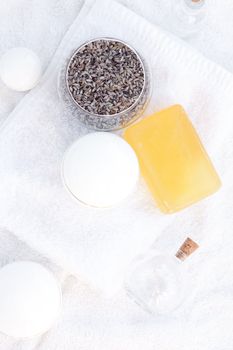 cosmetic containers, bottles, soap and lavender on a white towel