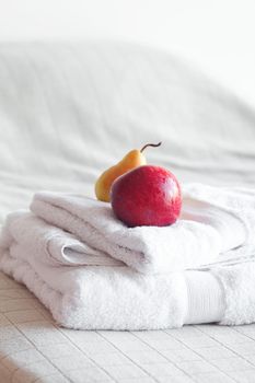 apple and pear on towels on the bed 