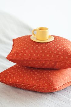 cup lying on pillows on the bed