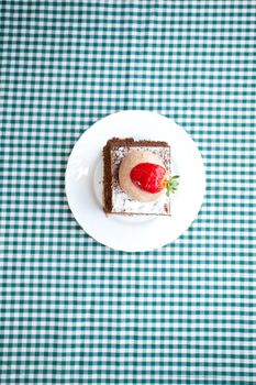 beautiful cake with strawberry on plaid fabric