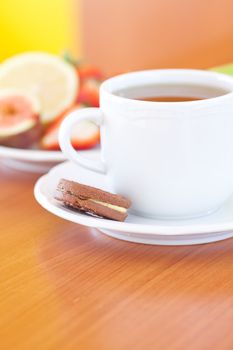 cup of tea,cookie,apple, lemon, fig and strawberries on a plate