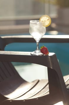 Swimming pool, lounge, a wine glass with ice, lemon and strawberry