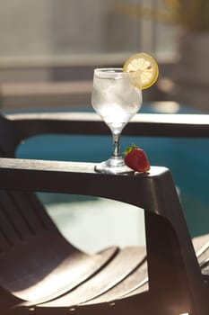 Swimming pool, lounge, a wine glass with ice, lemon and strawberry