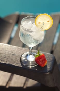 Swimming pool, lounge, a wine glass with ice, lemon and strawberry