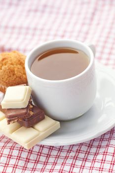 bar of chocolate,tea and muffin on plaid fabric