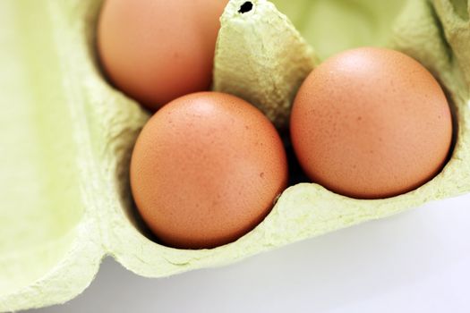 Fresh brown hens eggs for a healthy breakfast in a cardboard egg box suitable for recycling, closeup overhead view