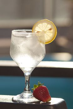 Swimming pool, lounge, a wine glass with ice, lemon and strawberry