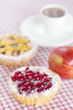 beautiful cake with berries,apple and tea on plaid fabric