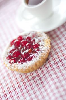 beautiful cake with berries and tea on plaid fabric