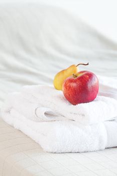 apple and pear on towels on the bed 