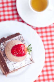 beautiful cake with strawberry and tea on plaid fabric