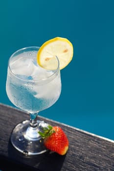 Swimming pool, lounge, a wine glass with ice, lemon and strawberry