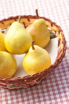 pears in a wooden basket  lying on a plaid fabric 