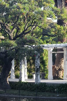 Beautiful white colonnade in the park with green trees