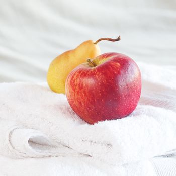 apple and pear on towels on the bed 