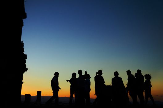 Silhouettes of a group of people on the roof the cathedral in Mexico City with skyscrapers in the background at sunset