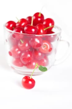 cherry with green leaf and a cup of cherries on a white background