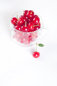 cherry with green leaf and a cup of cherries on a white background