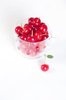 cherry with green leaf and a cup of cherries on a white background