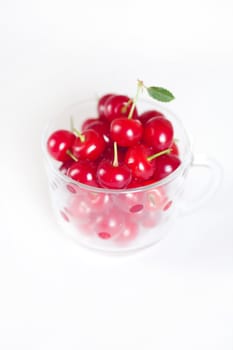 cherry with green leaf and a cup of cherries on a white background