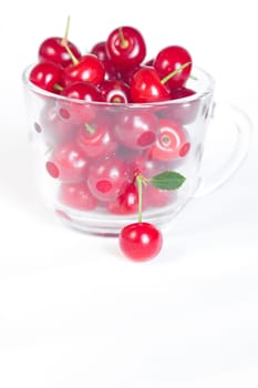 cherry with green leaf and a cup of cherries on a white background