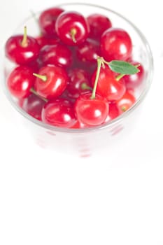 cherry with green leaf and a cup of cherries on a white background