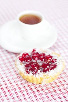 beautiful cake with berries and tea on plaid fabric