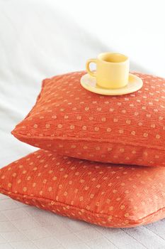 cup lying on pillows on the bed