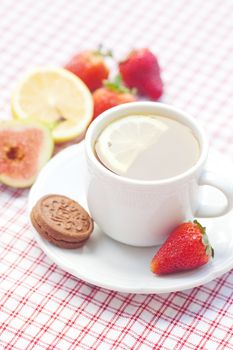 cup of tea,cookie, fig and strawberries on a plate