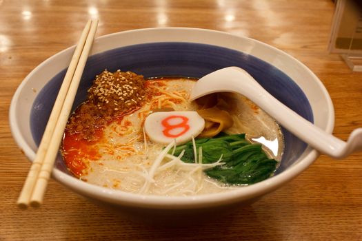 pork bone soup noodle with spicy ground pork garnished with Japanese spring onion, pak choi, kamaboko, sesame seeds and memma