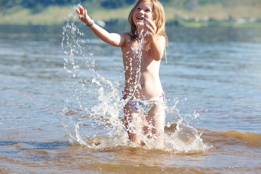 beautiful little girl splashes in the water