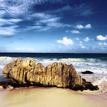 Rock on the beach with dramatic sky on square format 