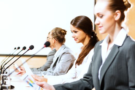 businessmen communicate at the conference, sitting at the table, on the table microphones and documents