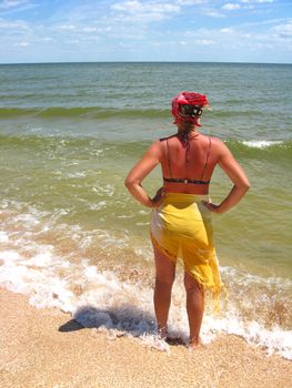 The girl in bathing suit standing at the seacoast