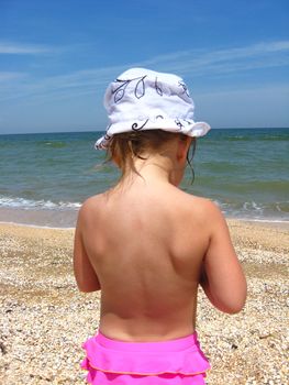 The back of little girl standing near the sea