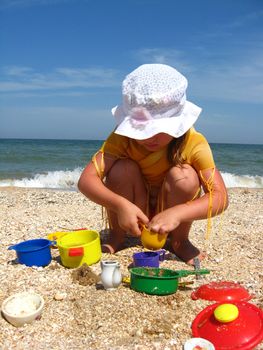 little girl plays on the sand at the sea