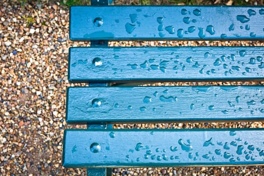 Rain drops on a blue park bench