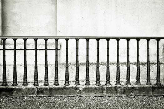 Monochrome image of wrought iron railings against a stone wall