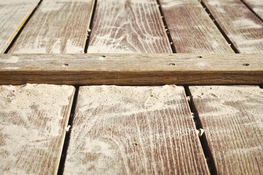 Close up of a wooden surface with sand on it