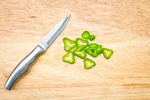 Chopped green chilli on a wooden board with a knife