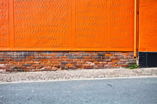 Bright orange wall with a sloping pavement as a background
