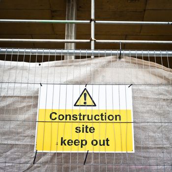 Construction site sign against a metal fence