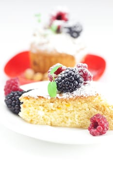 muffin with whipped cream, cake with icing, raspberry, blackberry and mint on a plate