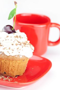 muffin with whipped cream, cherries and red cup on white background