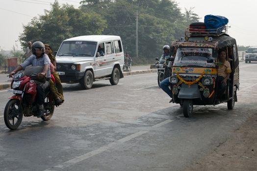 AGRA, INDIA - NOVEMBER 15: Overloaded motorcycles, cars and tuk-tuks drive on covered by haze Ring road (Delhi - Agra) on Nov 15, 2012 in Agra, India